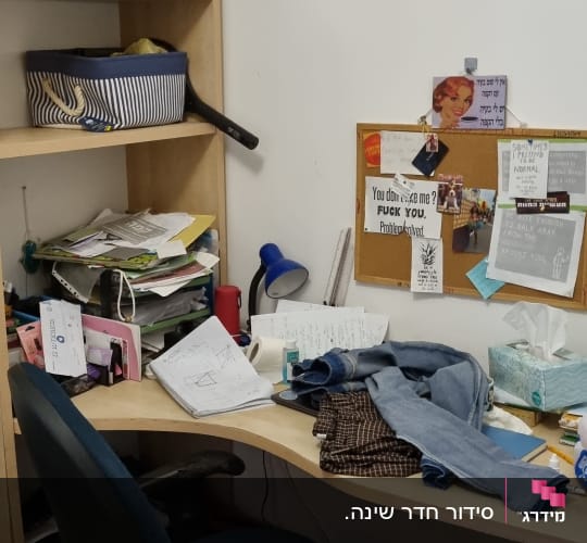 שולחן עבודה מבולגן עם ניירות, בגדים וכלי כתיבה